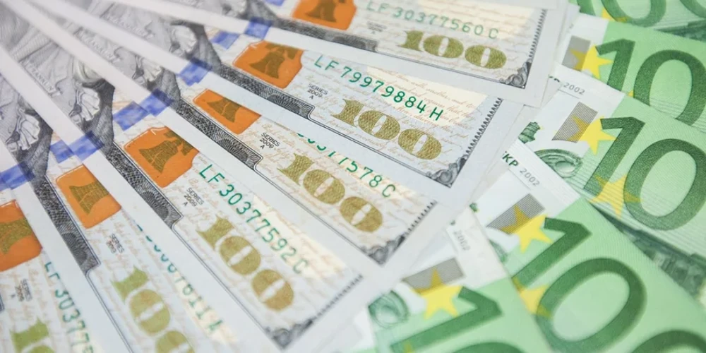 Банкноти долара та євро на тлі офіційної таблиці курсів НБУ